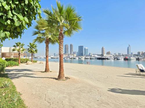 two palm trees on a sandy beach near the water at Seaside Serenity Perfect Beachfront Holiday Haven in Dubai