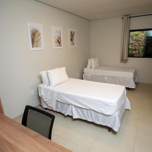 a room with two beds and a table at Hotel Pousada da Gruta in Caratinga
