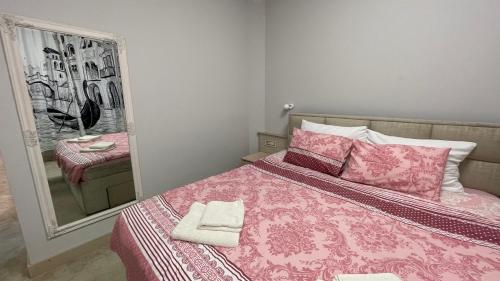 a bedroom with a pink bed with pillows and a mirror at SMART in Niš
