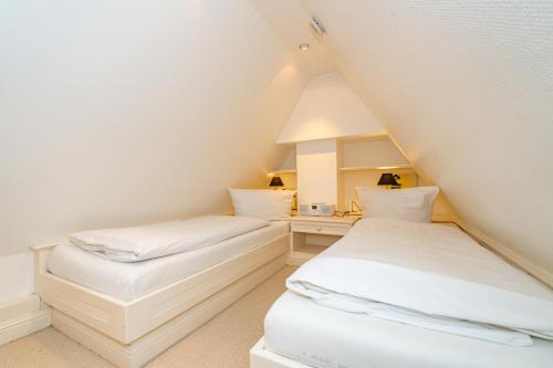 zwei Betten in einem Dachzimmer mit weißen Laken in der Unterkunft Friesenhaus Horsum Huis Friesenhaus Morsum Huis in Morsum