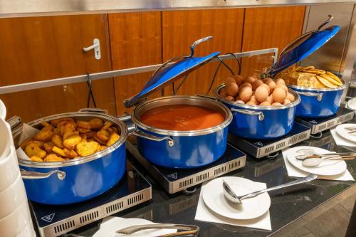 a buffet with four pots of food on a table at Wyndham Wroclaw Old Town in Wrocław