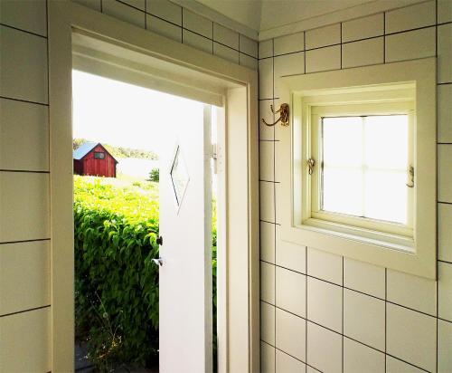 an open door with a window and a red barn at 1C, Första parkett, 50m till badstrand in Byxelkrok