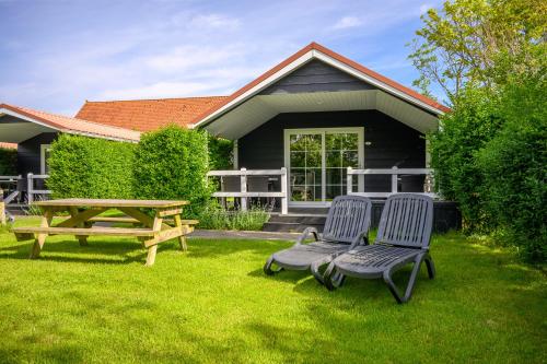 two chairs and a picnic table in front of a house at Lodges De Driesprong Domburg in Domburg