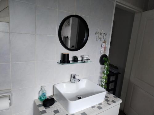 ein Badezimmer mit einem weißen Waschbecken und einem Spiegel in der Unterkunft Jan's Cottage in Centurion