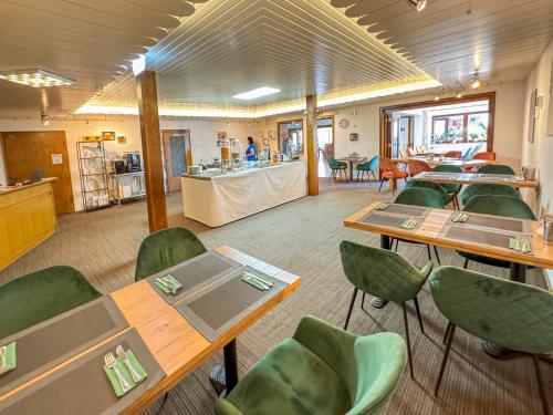 a cafeteria with tables and green chairs and a counter at Berghotel Waidmannsheil in Battenberg