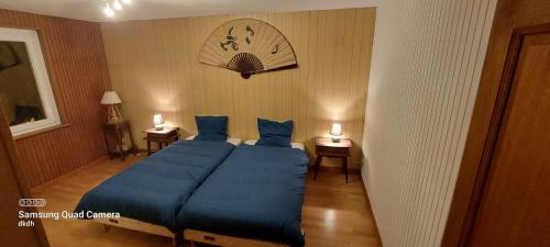 - une chambre avec un lit bleu et 2 tables de nuit dans l'établissement Gite domaine fontaine stanislas, à Plombières-les-Bains