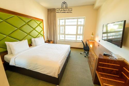 a bedroom with a bed and a flat screen tv at Holyland Hotel Amman in Amman