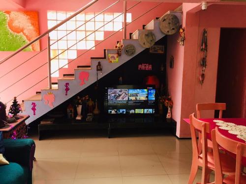 a room with a staircase with a television and a stair case at Casa da Barbie da Serra in Pacoti
