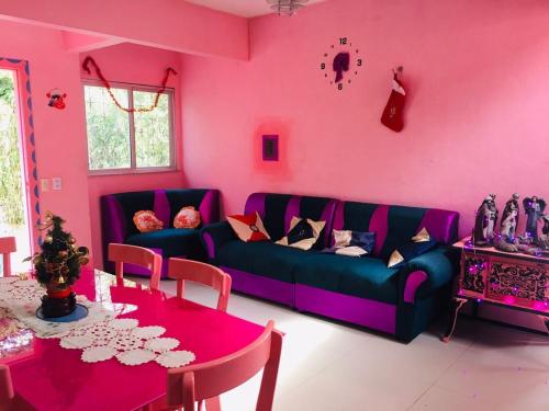 a living room with a purple couch and a table at Casa da Barbie da Serra in Pacoti