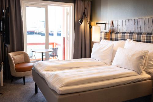 a hotel room with a bed and a chair and a window at Scandic Svolvær in Svolvær