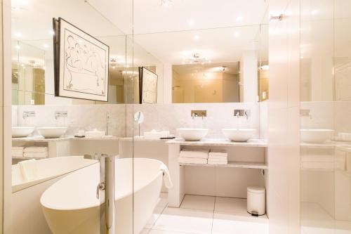 a white bathroom with three sinks and a shower at Restaurant Hotel Merlet in Schoorl