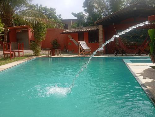 a pool with a water fountain in front of a house at guesthouseparacuru in Paracuru