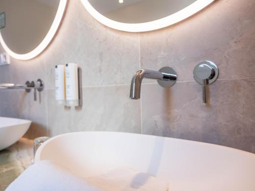 a bathroom with a tub and a sink and a mirror at Restaurant Hotel Merlet in Schoorl