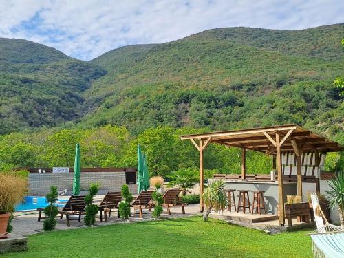 a pavilion with chairs and a table with mountains in the background at Vila Nikola in Demir Kapija