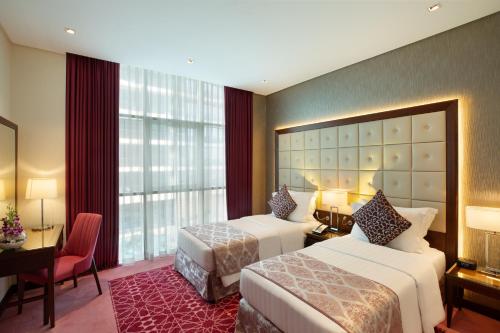 a hotel room with two beds and a desk and a window at Royal Continental Suites Business Bay - Deluxe Apartments in Dubai