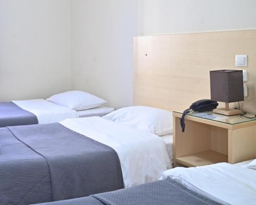 a hotel room with three beds and a television at Kentrikon in Chalkida