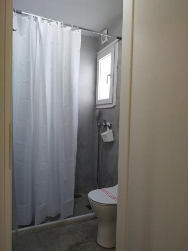 a bathroom with a white shower curtain and a toilet at Kentrikon in Chalkida