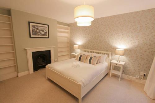 a bedroom with a white bed and a fireplace at Large clifton one bed flat and parking in Bristol