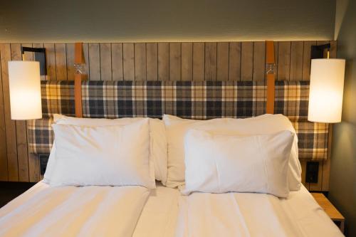 a bedroom with a bed with white pillows and two lights at Scandic Svolvær in Svolvær