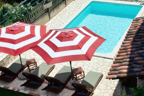two red and white umbrellas and chairs next to a swimming pool at Apartments Oliva in Fiorini