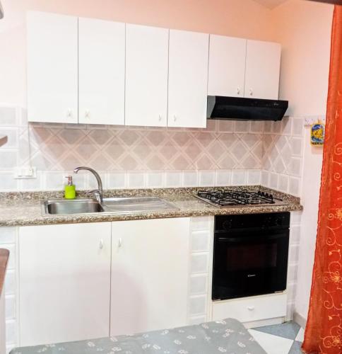 Una cocina con gabinetes blancos y un fregadero. en SANGIORGIO Beachfront APT, en San Giorgio