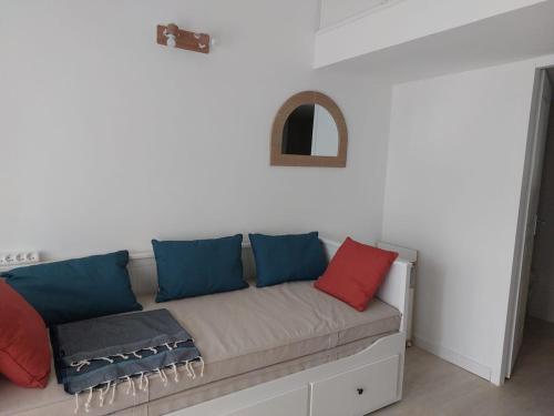 - un canapé avec des oreillers rouges et bleus dans l'établissement Studio 25m2, à LʼIsle-sur-la-Sorgue