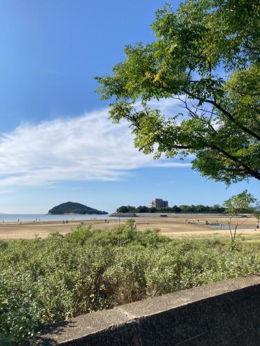 a view of a beach with people on the sand at 一軒宿 百々 private house rental doudou in Mitoyo