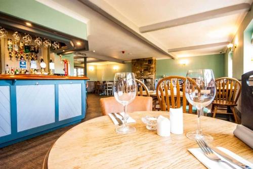 a wooden table with two wine glasses on it at The Chequers Inn in Rookley