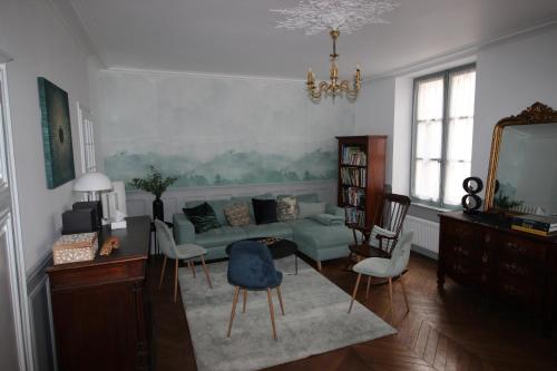 ein Wohnzimmer mit einem grünen Sofa und Stühlen in der Unterkunft Maison Bourgeoise classée 3 étoiles à 100 m des Bords de Loire avec parkings privés in Orléans