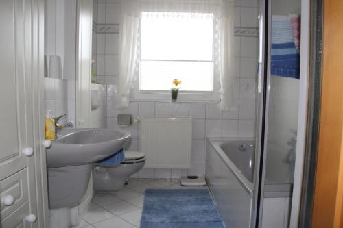 a white bathroom with a sink and a toilet and a window at Ferienwohnung Katzan in Ebstorf