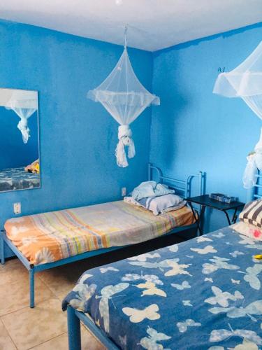 a bedroom with two beds and a blue wall at Casa da Barbie da Serra in Pacoti