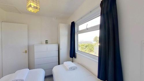 a bedroom with a window and a white bed and a window at B44 Sea Urchin, Riviere Towans in Hayle