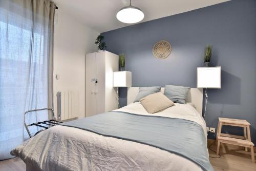 une chambre avec un lit et un mur bleu dans l'établissement Le Nid de Montbran - Avec balcon, à Matignon