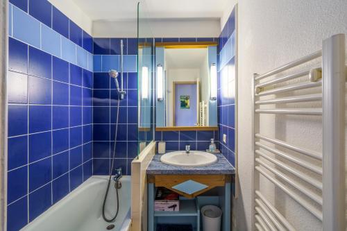 baño de azulejos azules con lavabo y bañera en Les Mousses - Superbe vue mer, en Bénodet