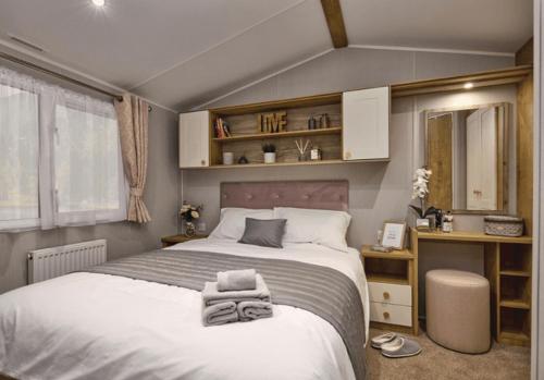 a bedroom with a large bed and a desk at Sandy Glade Holiday Park in Burnham on Sea
