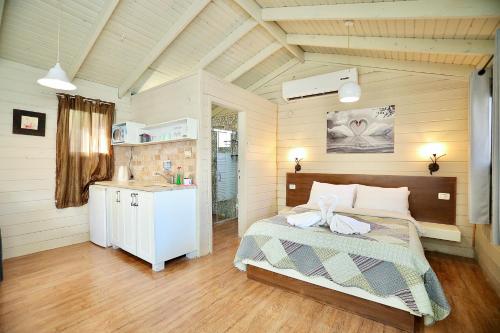 a bedroom with a bed and a kitchen in it at בקתות ספיר in Kallanit
