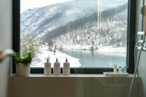 a window with bottles of wine on a ledge at Blackberry Cabin lakeside escape in Tubravić