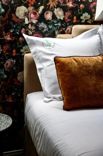 a bed with white pillows and a floral wallpaper at Hôtel Paulette Rouen Centre Cathédrale in Rouen