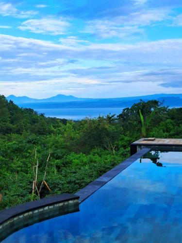 a swimming pool with a view of the ocean at Kubuhill Sunset Bungalow in Nusa Penida