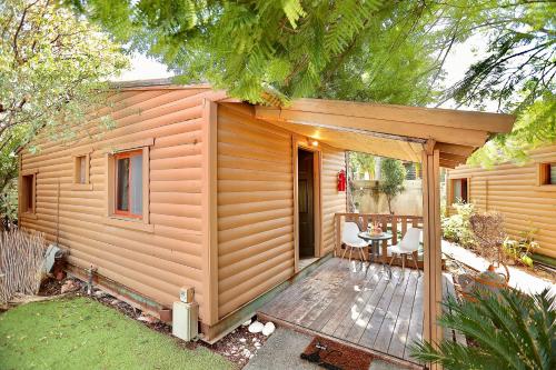 a small wooden cabin with a table on a deck at בקתות ספיר in Kallanit