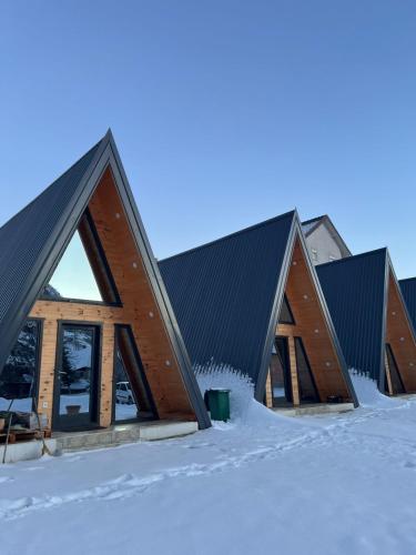 a group of three buildings in the snow at Camp Danis in Plav
