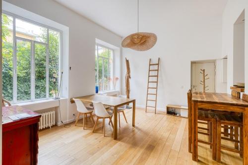 une salle à manger avec une table, des chaises et des fenêtres dans l'établissement Parisian Loft & Secret Garden, à Paris