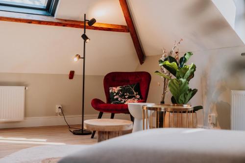 a living room with a red chair and a lamp at Jacques van Marken Erfgoed in Delft