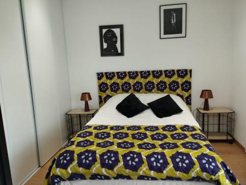 a bedroom with a bed with a yellow and blue blanket at 2 Chambres d'hôtes Chante-Coucou in Onet le Château