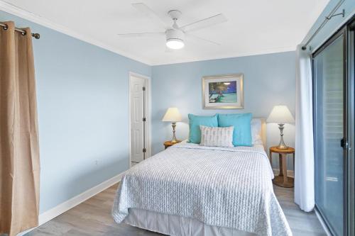 a blue bedroom with a bed and two lamps at 33C Lighthouse Point in Tybee Island
