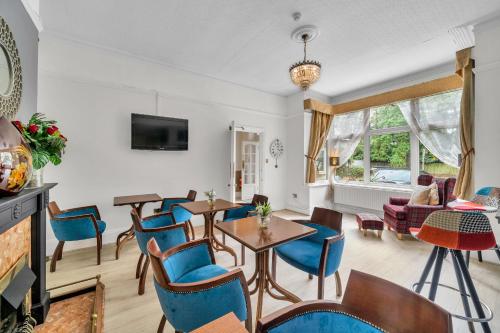 a living room with tables and chairs and a tv at Dial House Hotel in Crowthorne