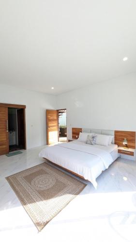 a white bedroom with a large bed and a rug at The Jungle Villa, Lombok in Mangsit
