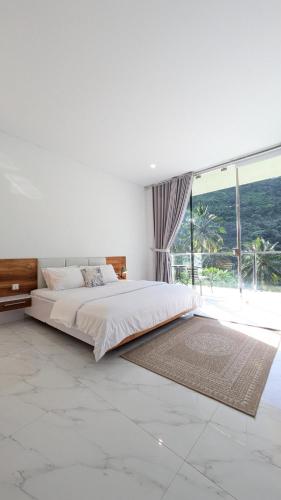 a bedroom with a large bed and a large window at The Jungle Villa, Lombok in Mangsit