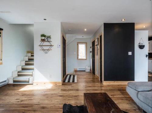a living room with a couch and a staircase at Yomi Chalet in Lac-Superieur