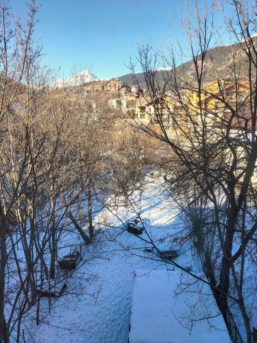 a snow covered river with trees and buildings in the background at Spacious 3 bedrooms apartment in Briançon